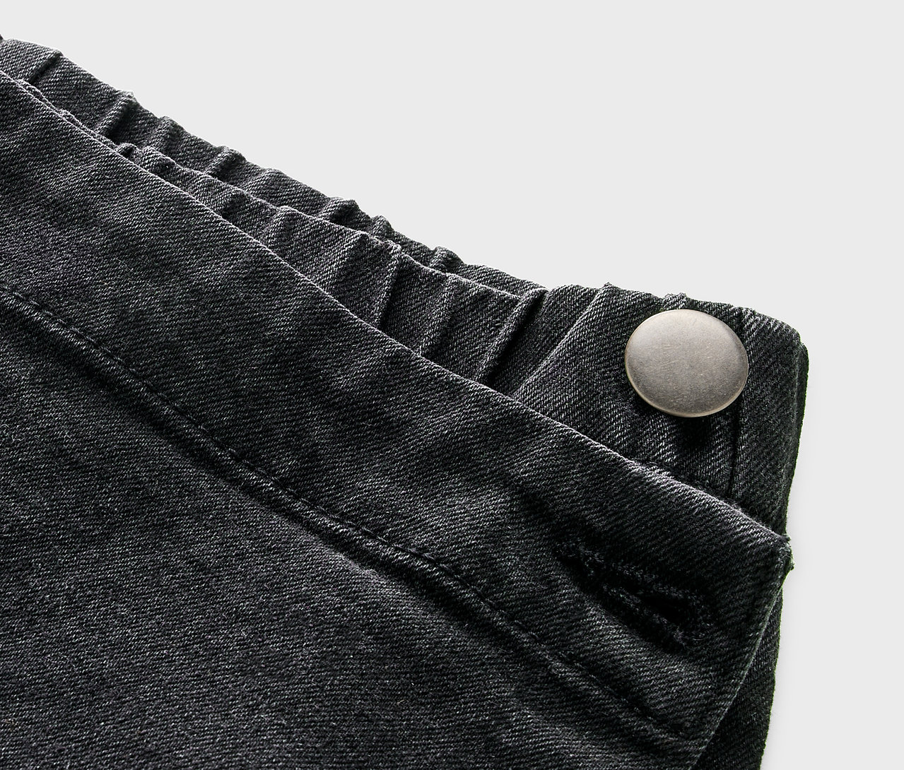 Detailansicht eines Kinder-Hosenrocks in Jeansoptik mit Knopf.