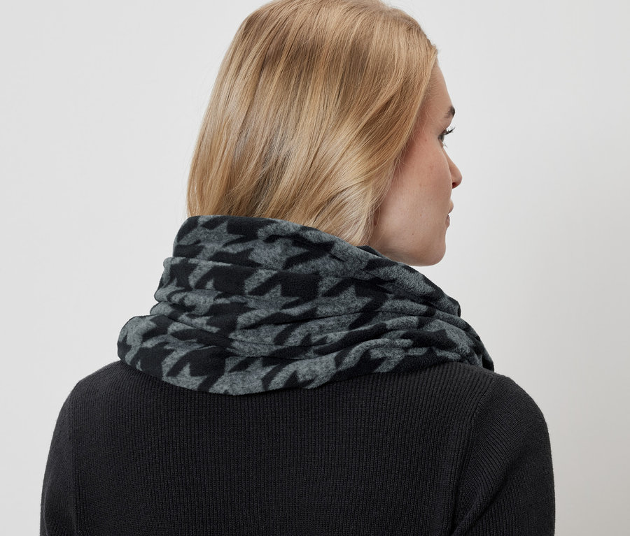 Frau trägt einen grau-schwarzen Hahnentritt-Schal und einen schwarzen Pullover.