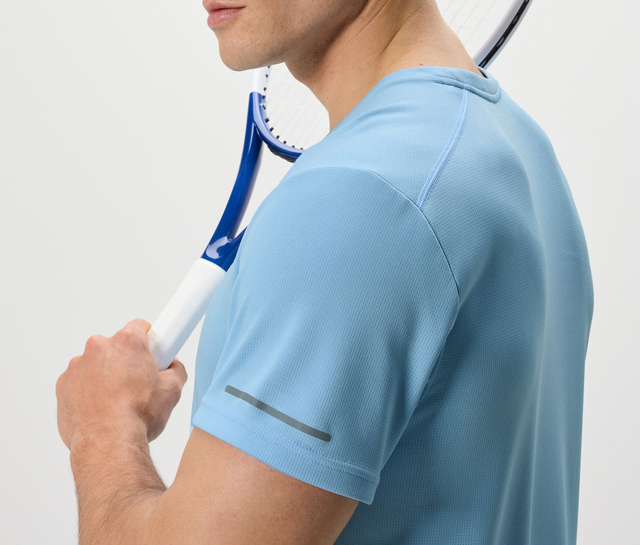 Mann mit Tennisschläger über der Schulter trägt ein hellblaues Funktionsshirt.