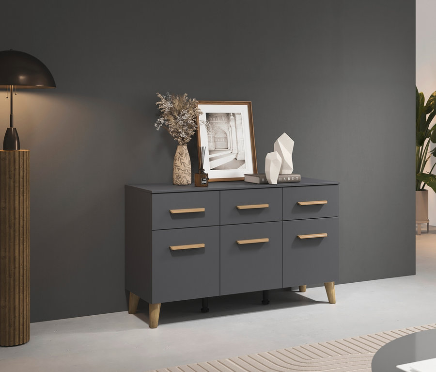 Graue Kommode mit sechs Schubladen steht neben einer Lampe und Blumen.