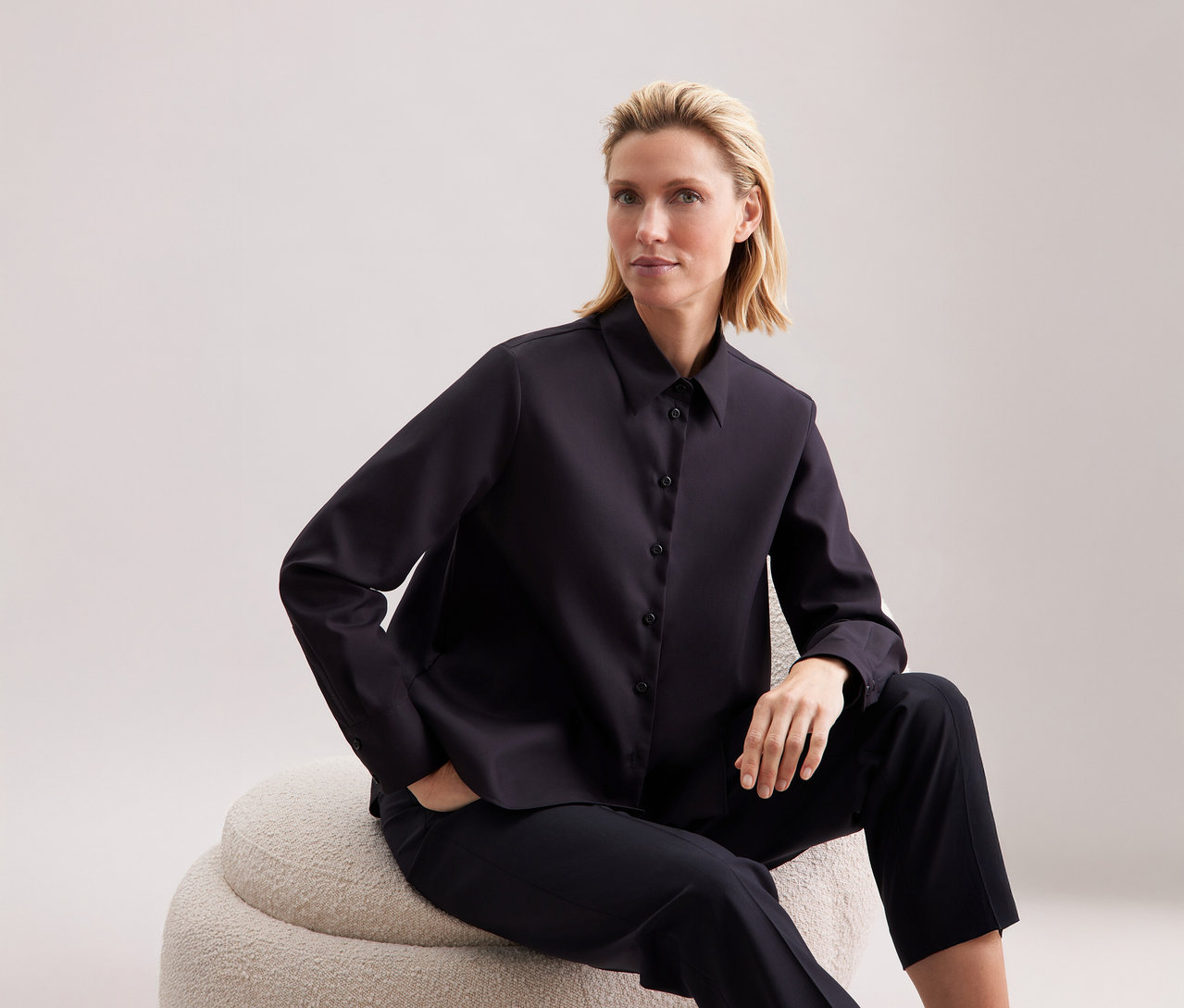 Frau sitzt und trägt eine Seidensticker Regular-Bluse.