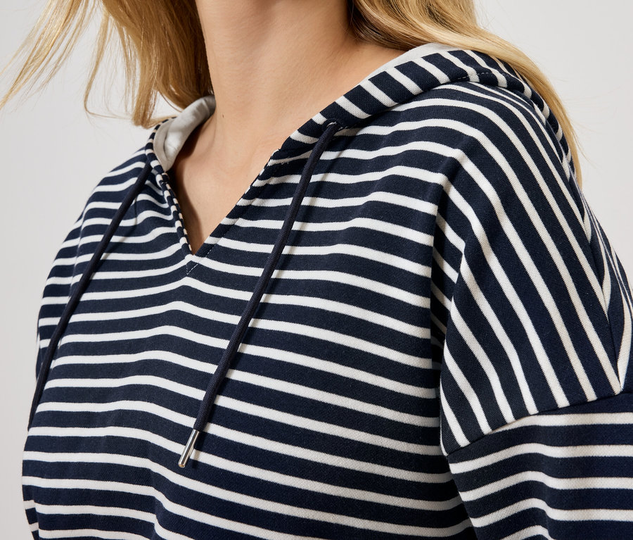 Blonde Frau trägt einen blau-weiß gestreiften Hoodie.