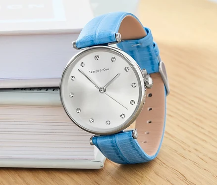 Eine Armbanduhr mit Lederband und Kristallen liegt auf Büchern.