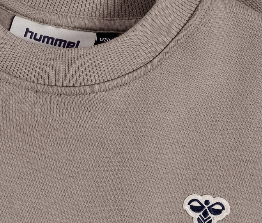 Nahaufnahme eines hellbraunen Hummel-Sweatshirts mit Rippstrickkragen und Hummel-Logo.