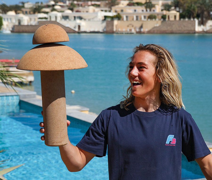Frau hält ein F2 Cork Balance Board Set Pill mit Korkrolle vor einem Pool.