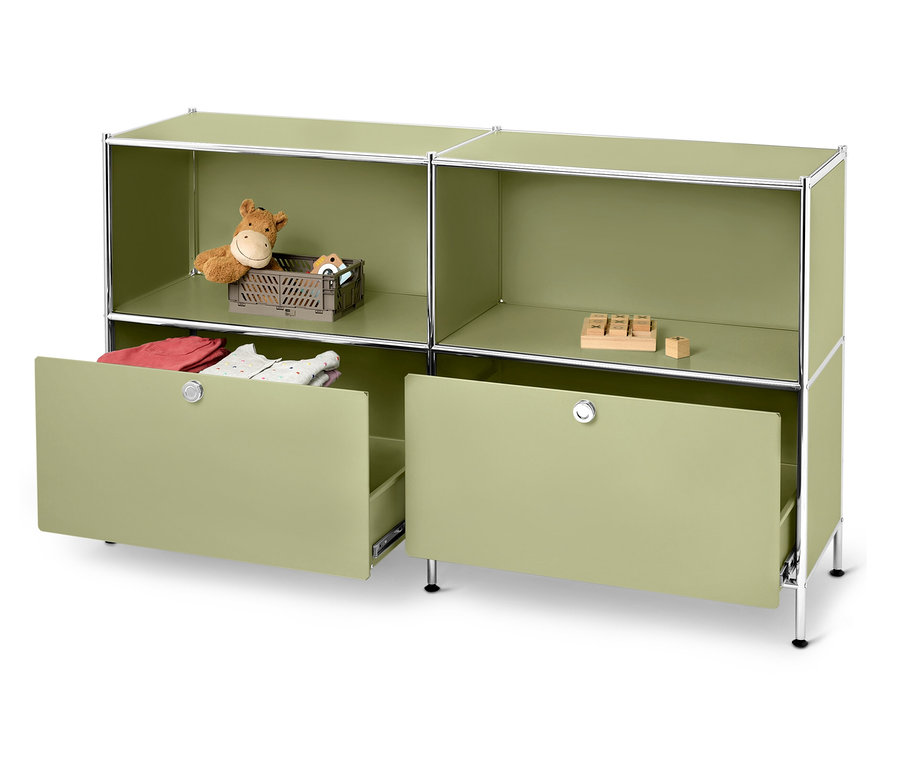 Ein grünes modulares Regal mit zwei offenen Fächern und zwei Schubladen, von denen eine teilweise geöffnet ist. In den Fächern befinden sich Spielzeug und im Schubfach Kleidung.