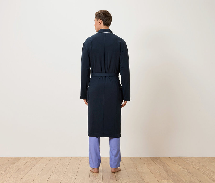 Ein Mann von hinten, der einen marineblauen Bademantel und hellblaue Pyjamahose trägt.