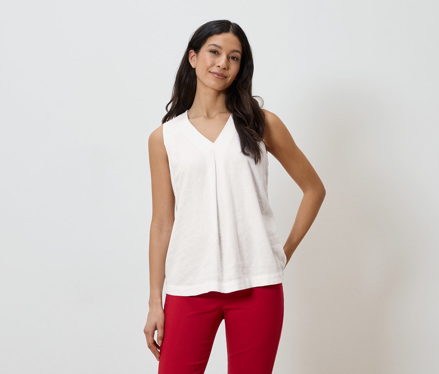 Frau trägt ein ärmelloses Oberteil in Weiß und eine rote Hose.