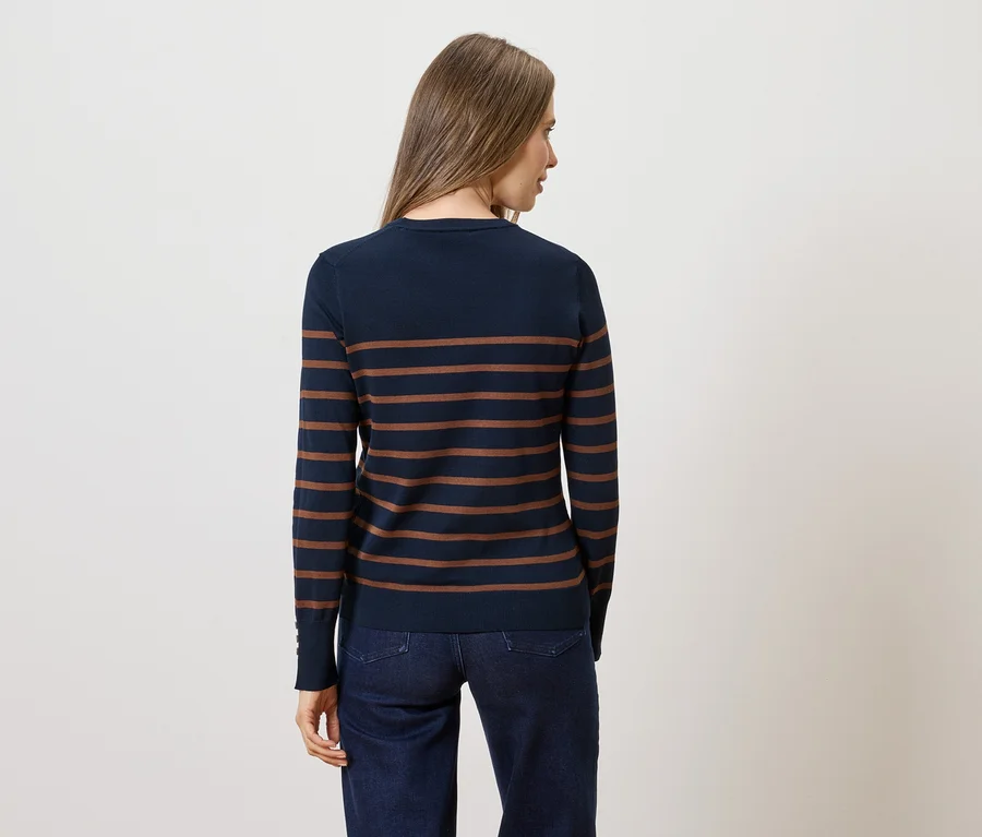 Frau von hinten in dunkelblau-braun gestreiftem Pullover und Jeans vor weißem Hintergrund.