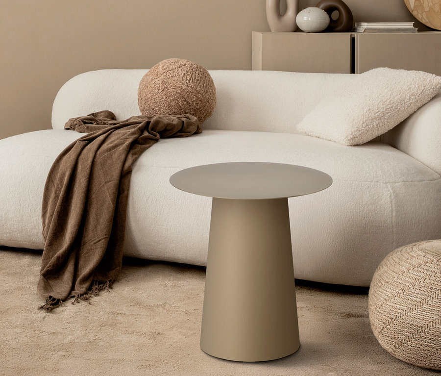 Beige Couch mit rundem Kissen, Decke und Beistelltisch auf Teppich.