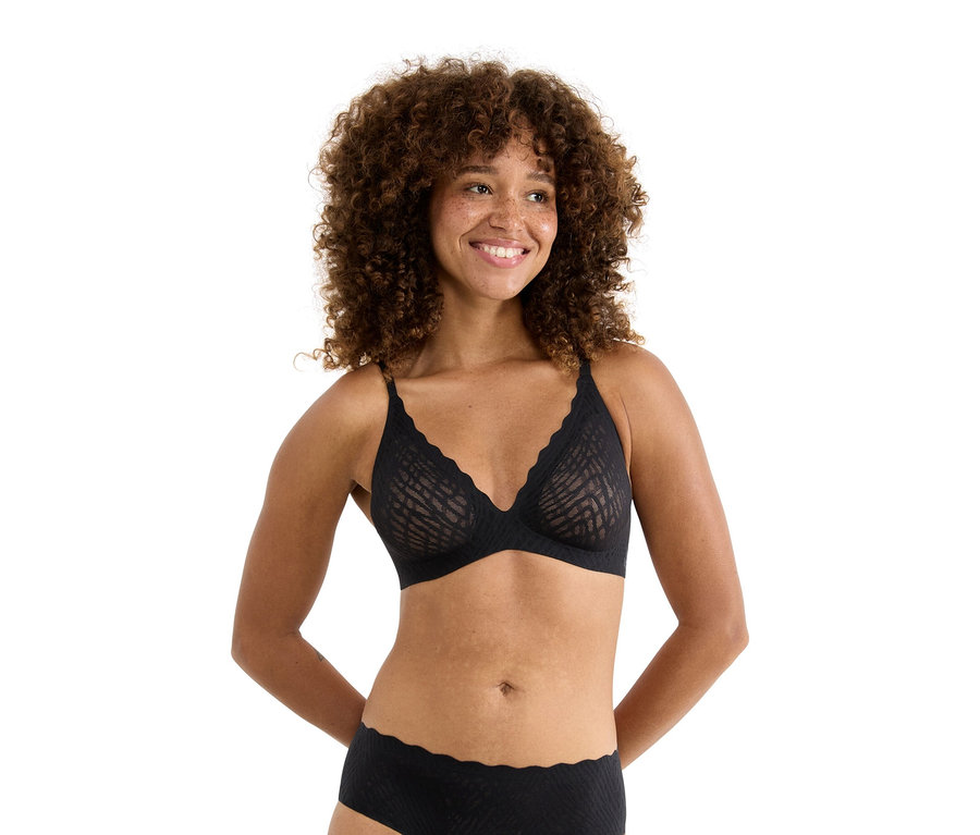 Frau mit lockigem Haar, die einen schwarzen BH und eine Unterhose trägt.