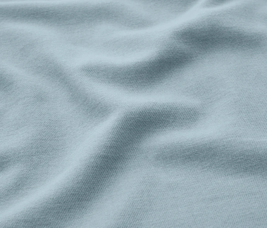 Helles blaues Stoffgewebe mit weichen Falten und Schatten.