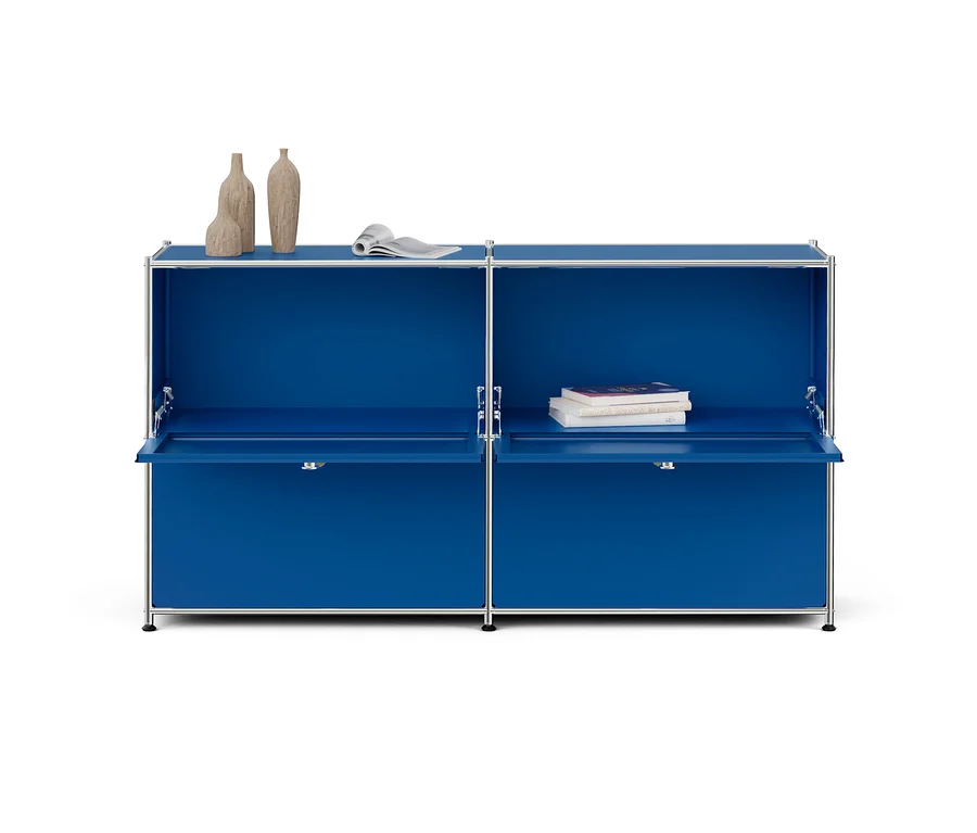 Blauer modularer Schrank mit Chromrahmen, zwei offenen Klapptüren und Dekoration. Links drei Vasen und eine Zeitschrift, rechts drei Bücher.