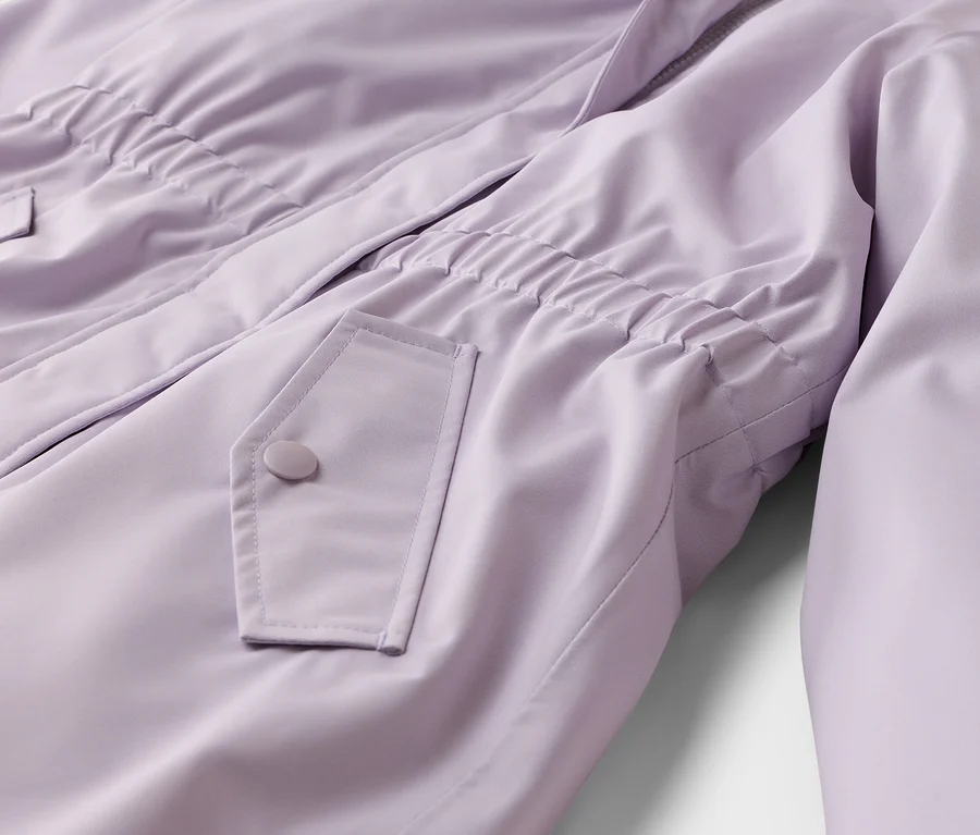 Nahaufnahme einer hellvioletten Jacke mit elastischem Bund, einer Pattentasche mit Knopf und einem teilweise sichtbaren Reißverschluss.