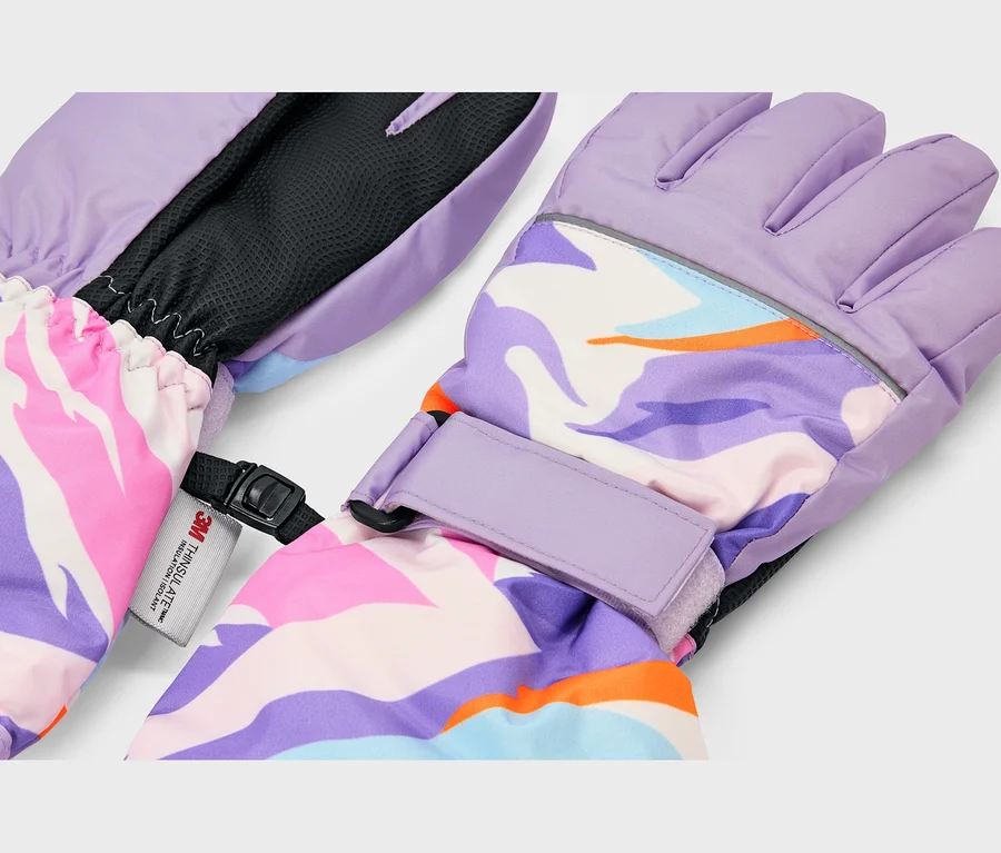 Ein Paar Winterhandschuhe mit abstraktem, farbenfrohem Muster in Lila, Pink, Blau, Orange und Weiß. Die Handschuhe haben hellviolette Handflächen, elastische Bündchen, verstellbare Handgelenksriemen und einen reflektierenden Streifen. Ein „3M Thinsulate Insulation“-Etikett ist sichtbar.