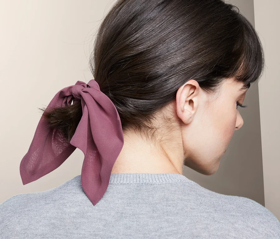 Frau trägt 2 Haargummis »Scrunchies« mit Schleife im Haar.