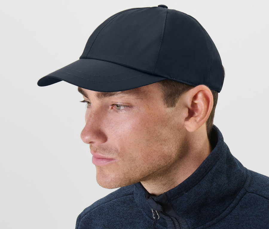 Mann trägt eine blaue Allwetter-Kappe und eine blaue Jacke.