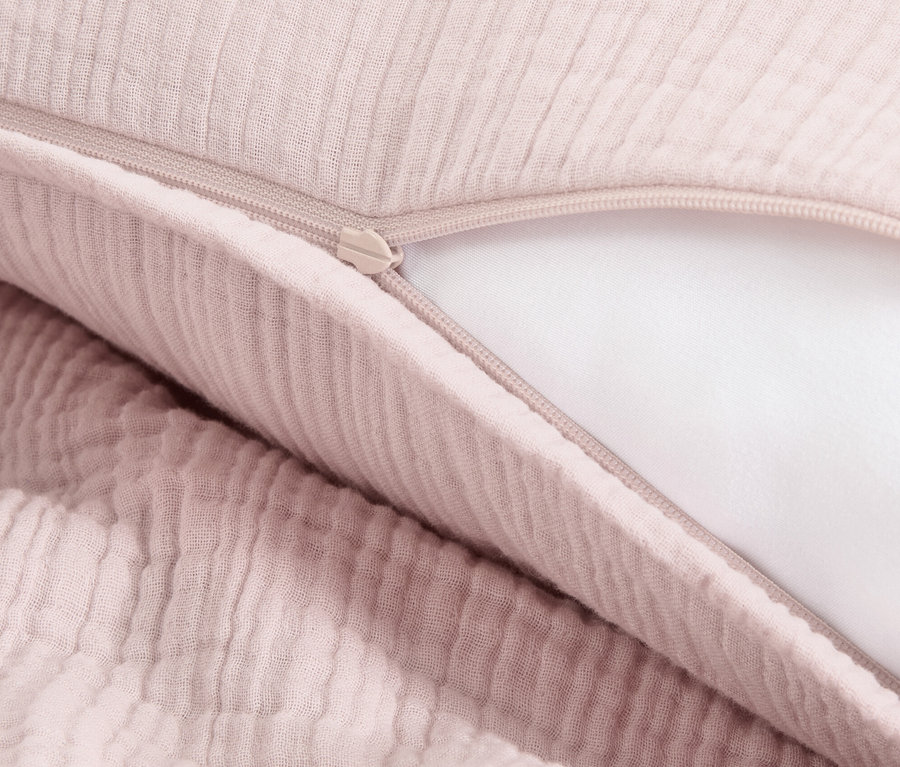 Detailansicht von rosafarbener Musselin-Bettwäsche mit Reißverschluss.