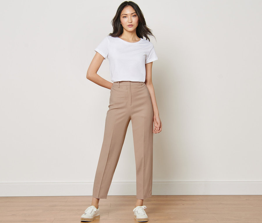 Frau posiert in weißem T-Shirt und Webhose.