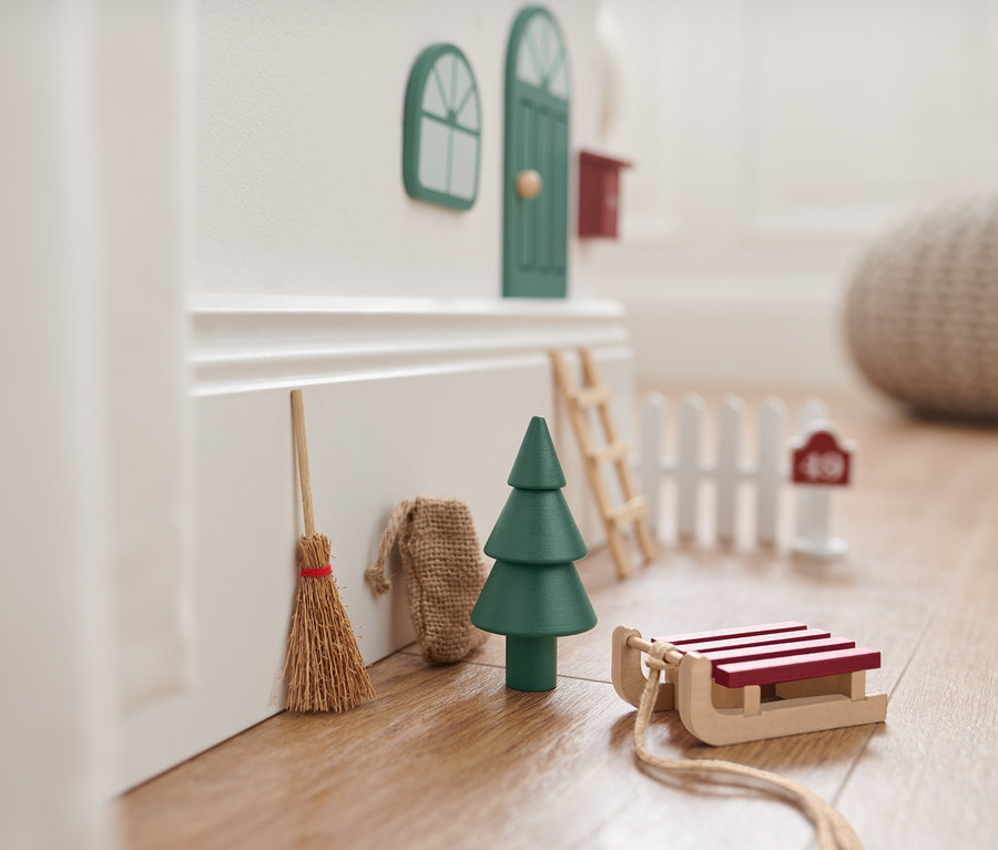 Dekorative Wichteltür-Accessoires an einer Wand, inklusive Besen, Baum, Schlitten und Leiter.