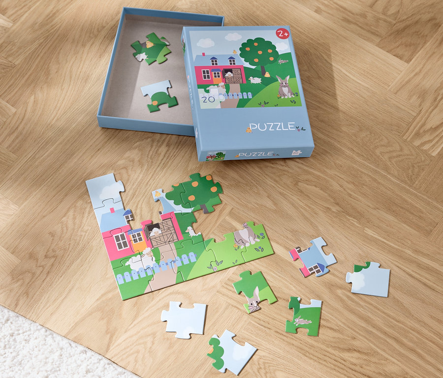 Ein teilweise zusammengesetztes Puzzle »Ostern« und eine Schachtel auf einem Holzboden.