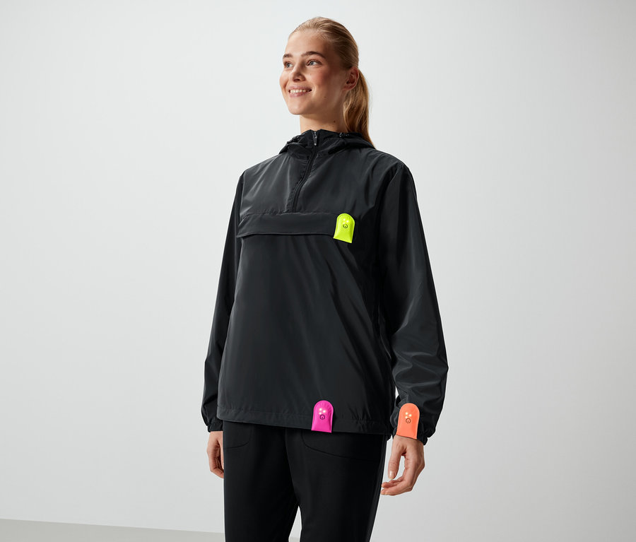 Frau lächelt in schwarzer Jacke mit neonfarbenen Details.