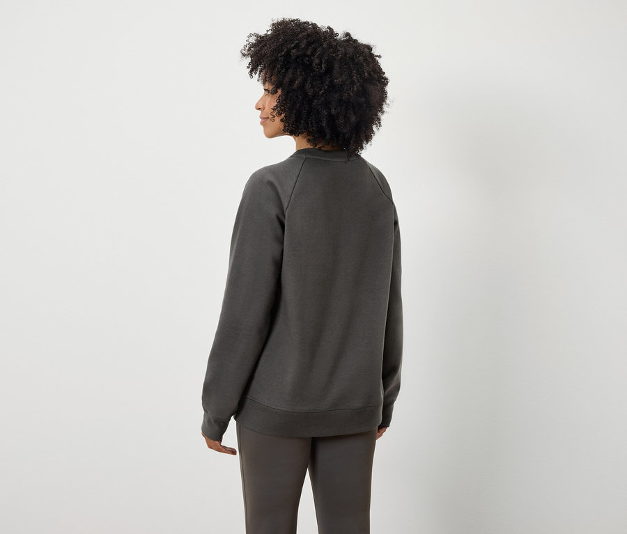 Rückansicht einer Frau mit Afro-Frisur in grauem Sweatshirt und Hose.