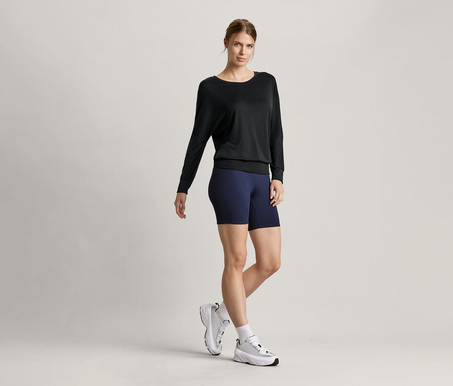 Frau trägt ein schwarzes Sport-und-Yogashirt und eine kurze Sporttight.