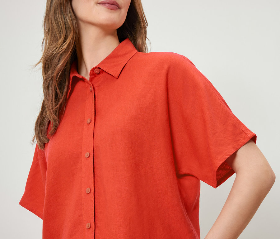 Detail einer orangefarbenen Leinenbluse für Damen.