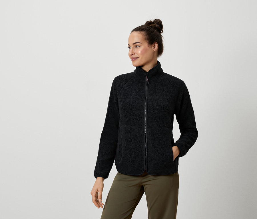 Frau trägt eine schwarze Fleecejacke und olivgrüne Hosen.