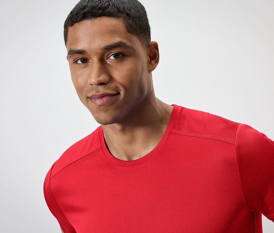 Porträt eines Mannes mit kurzen Haaren in einem roten T-Shirt.