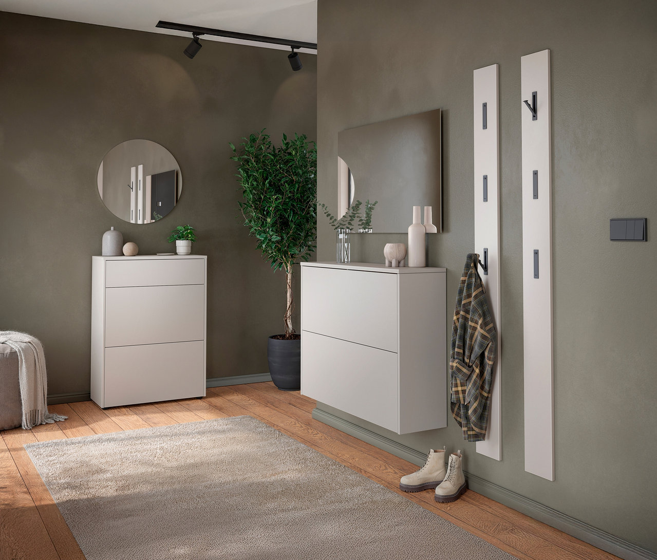 Flur mit zwei weißen Schuhschränken, einem runden Spiegel, einer Zimmerpflanze und einer Garderobe mit Jacke.