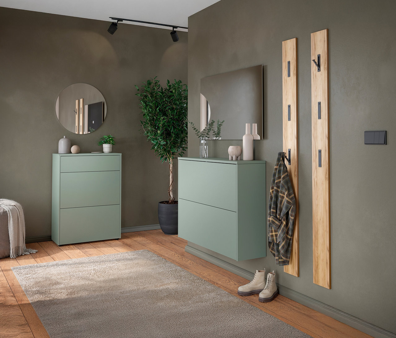 Eingangsbereich mit grünem Schuhschrank, Spiegel und Holzgarderobe an einer olivgrünen Wand.
