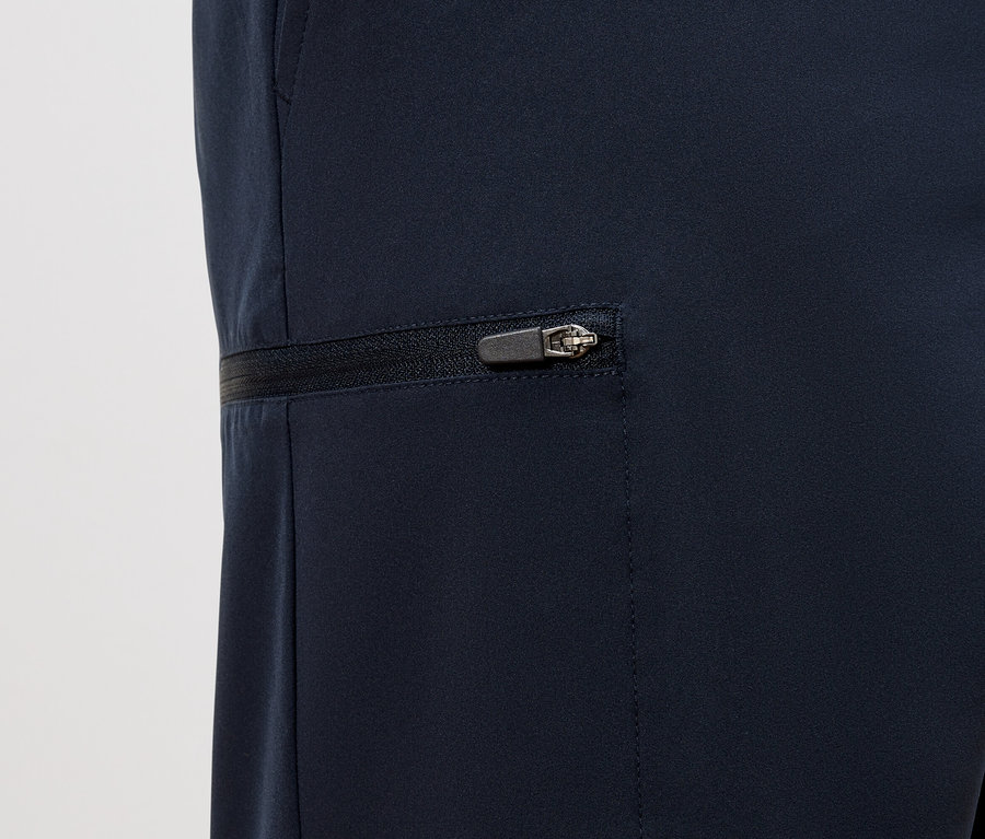 Detailaufnahme einer marineblauen Hose mit einem horizontalen Reißverschluss an der Tasche.