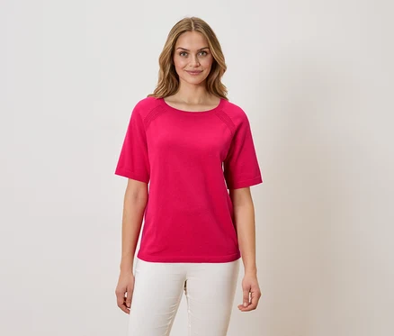 Frau trägt ein pinkes T-Shirt und weiße Hosen.