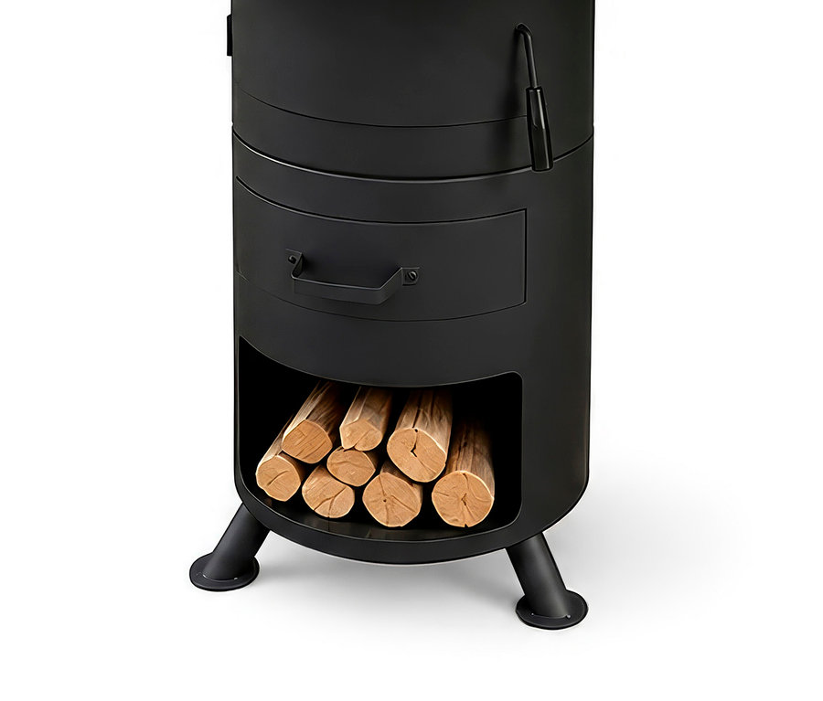 Schwarzer zylindrischer Outdoor-Ofen oder Kamin mit Griff oben, einer Schublade mit Griff und einem unteren Fach, gefüllt mit gestapeltem Brennholz, auf drei Beinen stehend.