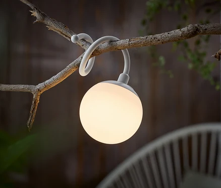 Eine weiße kugelförmige Lampe hängt an einem Ast.