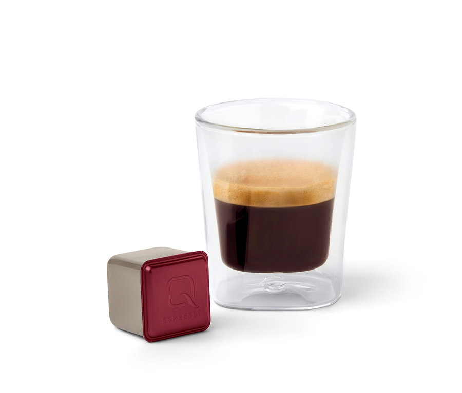 Eine Qbo Espresso APANECA ANA Kapsel steht neben einem Glas Espresso.