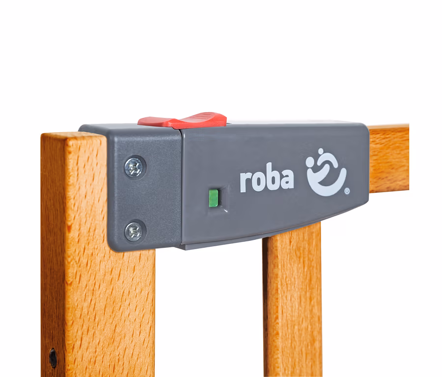 Nahaufnahme des grauen Verschlussmechanismus eines roba Türschutzgitters »Safety Up« mit rotem Knopf und grünem Indikator an Holzstäben.