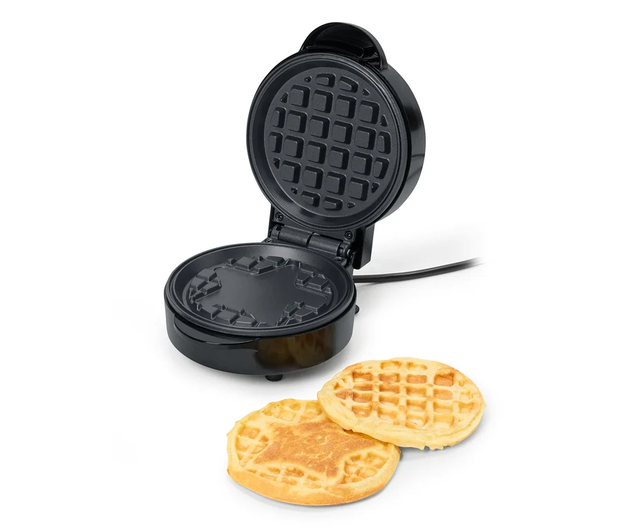 Geöffnetes Mini-Waffeleisen mit zwei fertigen Waffeln davor.