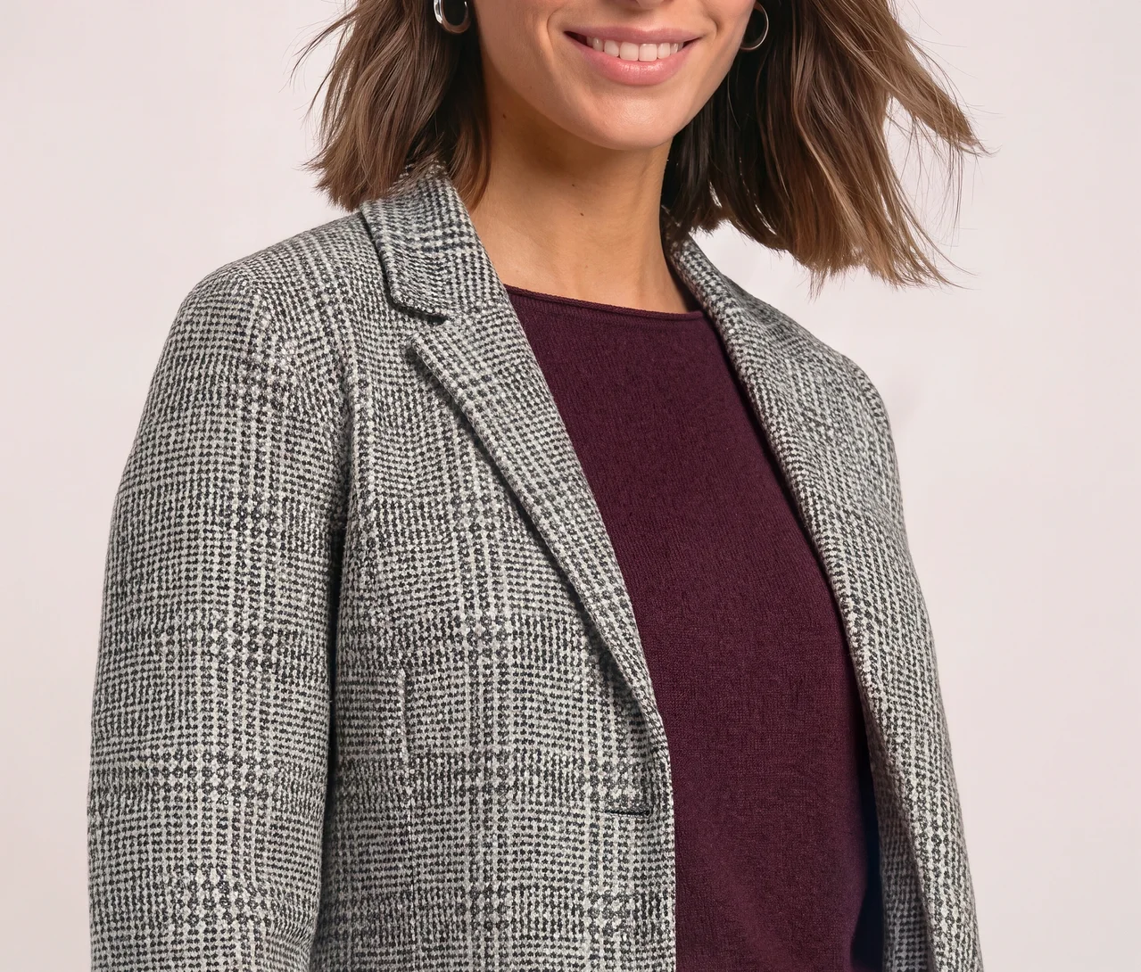 Lächelnde Frau mit kurzen braunen Haaren trägt einen grau-weiß karierten Street One Blazer über einem dunkelroten Oberteil.