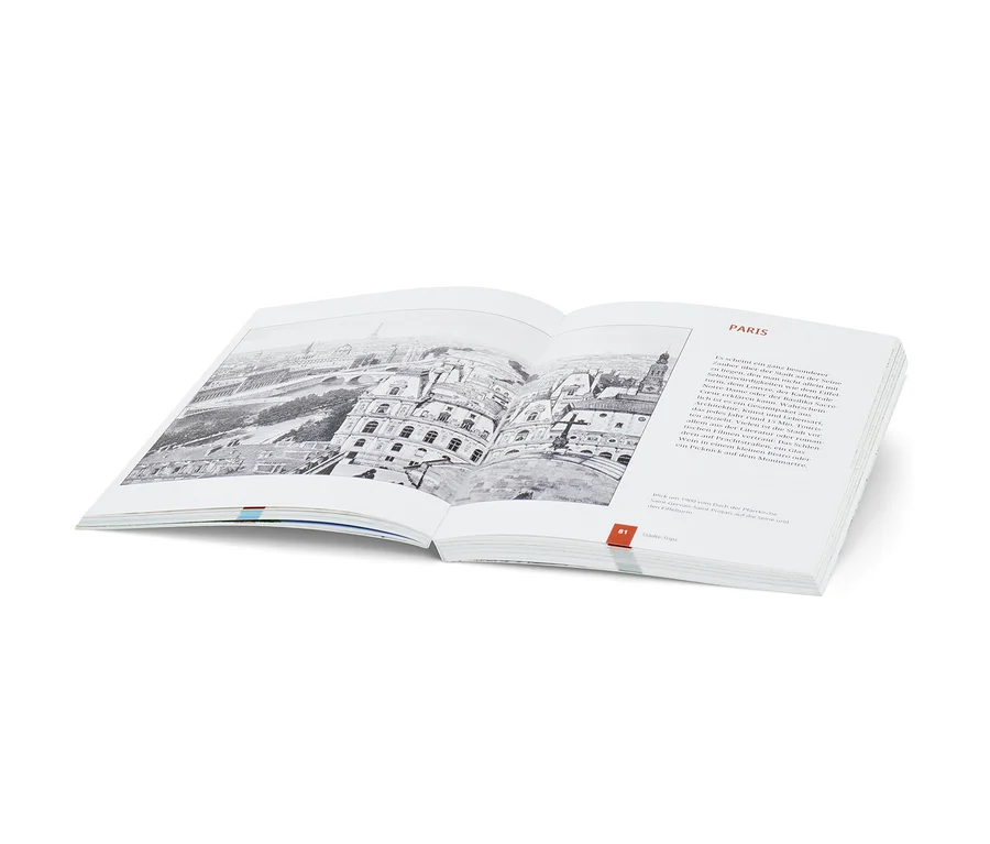 Offenes Buch mit Schwarzweißbild von Paris. Buch: Landkarten-Rätselbuch »Weltreise«.