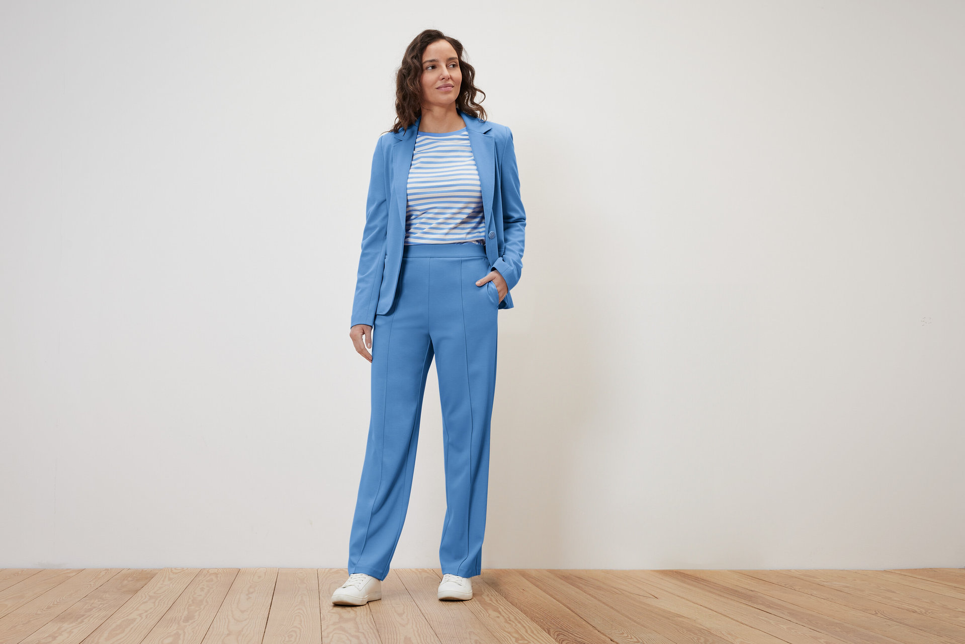 Frau posiert in blauem Sakko und Jerseyhose mit Biese.