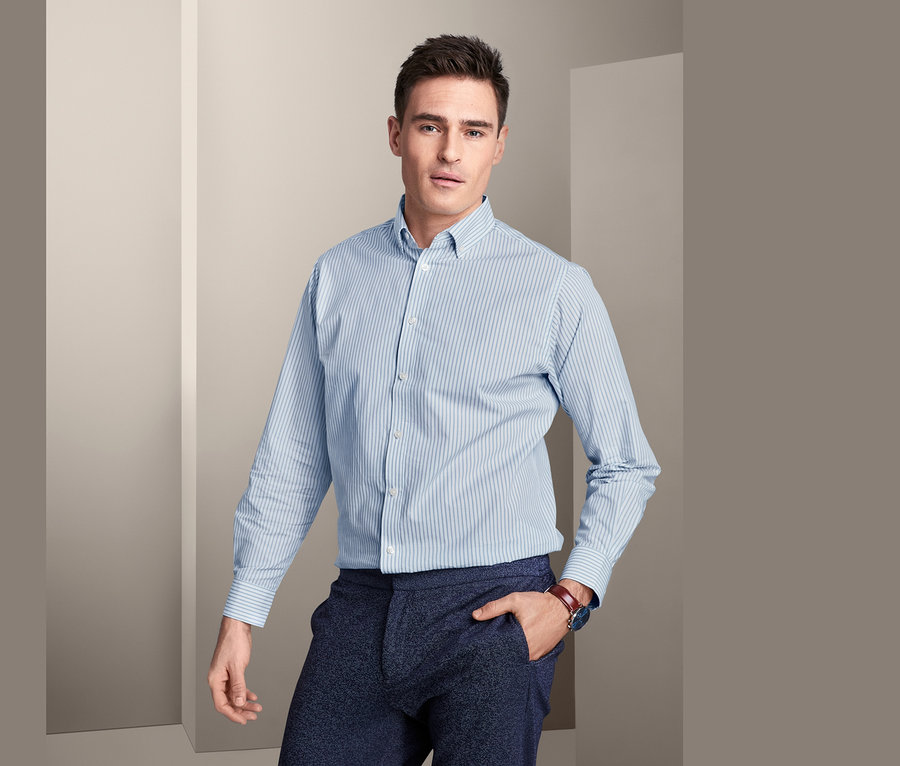 Mann posiert in einem Hemd mit Button-down-Kragen, Comfort Fit, und einer Hose.