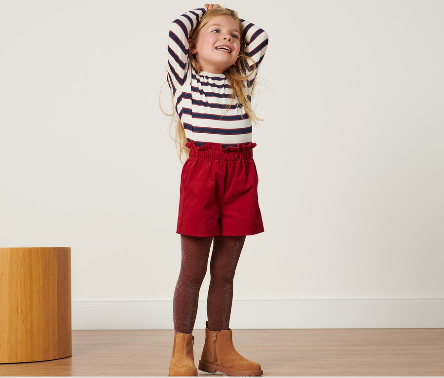 Mädchen posiert in Kleinkinder-Samtshorts.