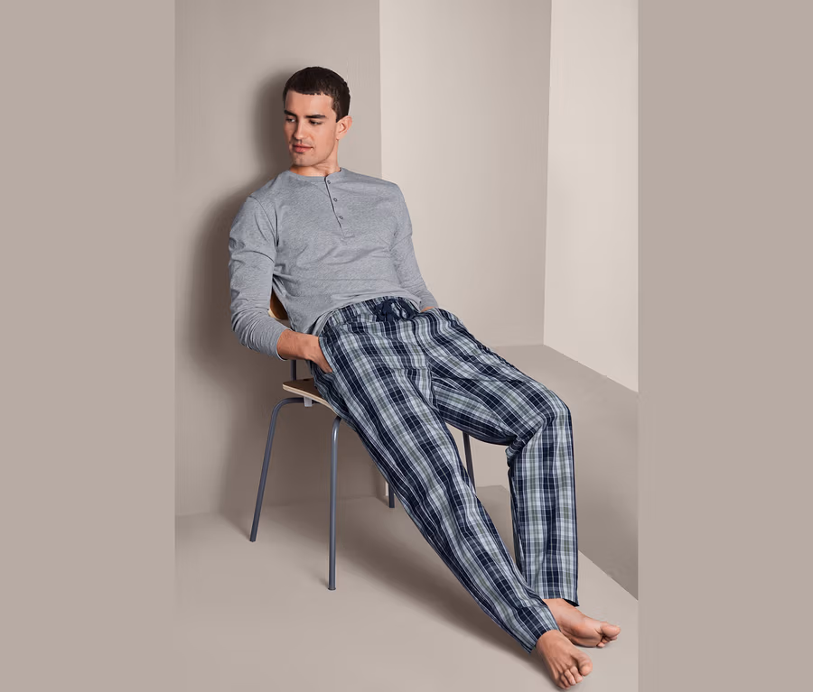 Mann sitzt auf einem Stuhl und trägt einen Pyjama.