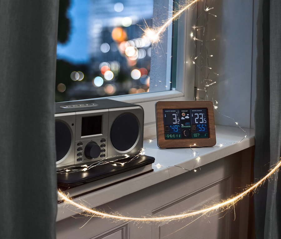 Ein WLAN-Internetradio mit Farbdisplay und eine Funk-Wetterstation mit LC-Farbdisplay und Außensensor stehen auf einem Fensterbrett.