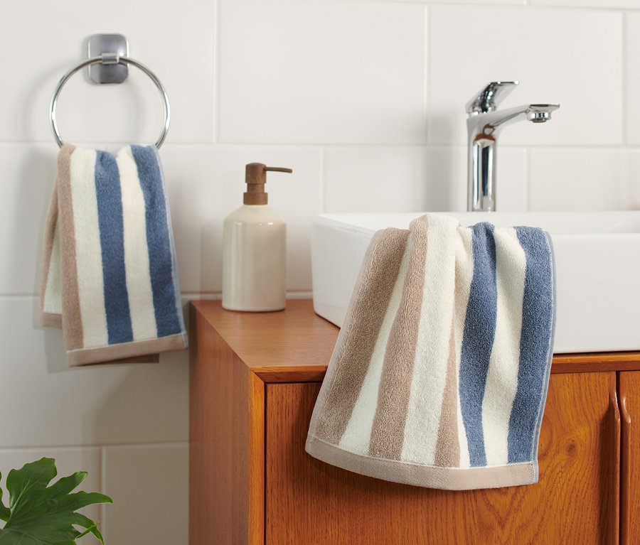 Zwei hochwertige, blau-weiß-beige gestreifte Gästehandtücher hängen im Badezimmer.