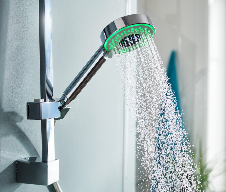 Wasser fließt aus einem LED-Duschkopf mit Wasserverbrauchsanzeige.