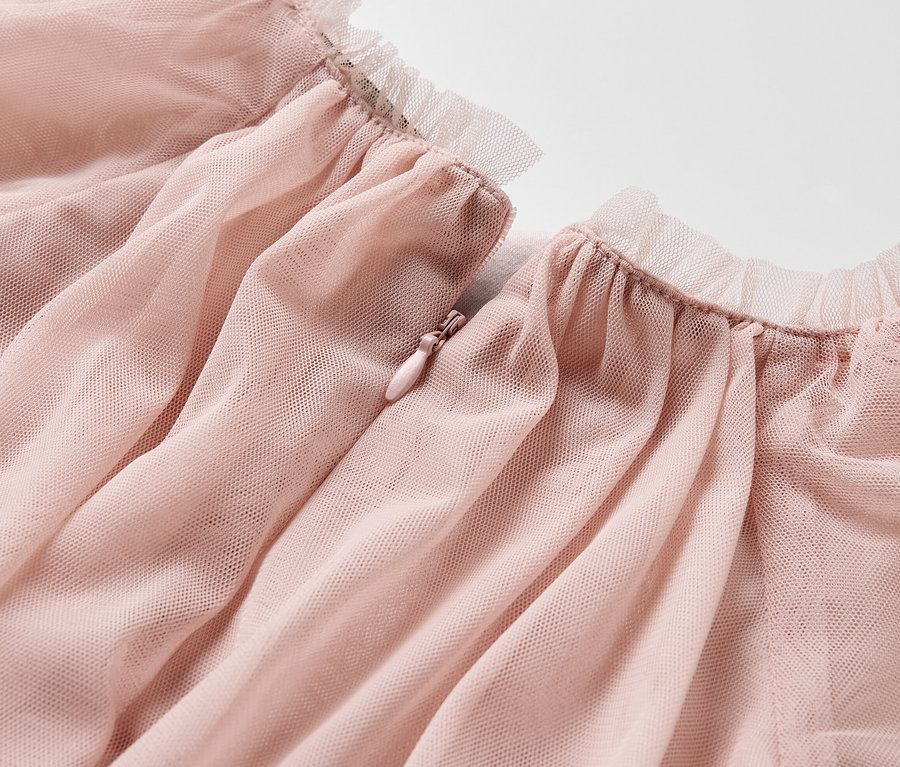 Detailansicht eines rosa Kinder-Tüllkleids mit Rüschensaum und Reißverschluss.